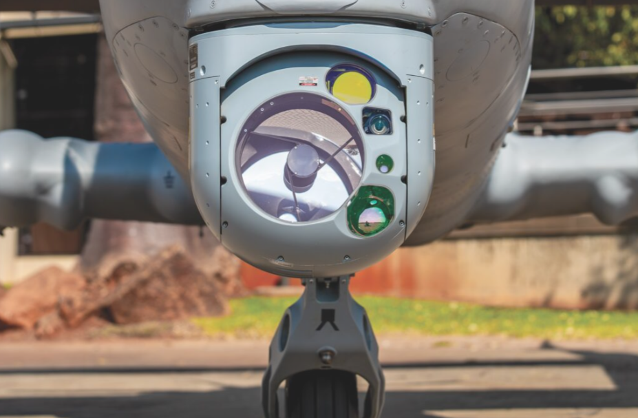 A South African Mwari light attack aircraft in flight, equipped with an advanced sensor turret under its nose, conceptualizing the integration of the ASELFLIR-500.