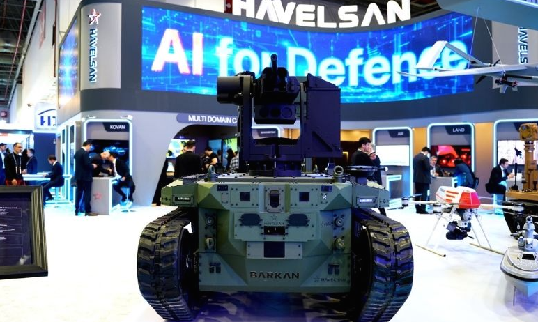 A military operator looking at multiple high-tech glowing screens in a dark command and control center, conceptualizing HAVELSAN's defense software and combat management systems.